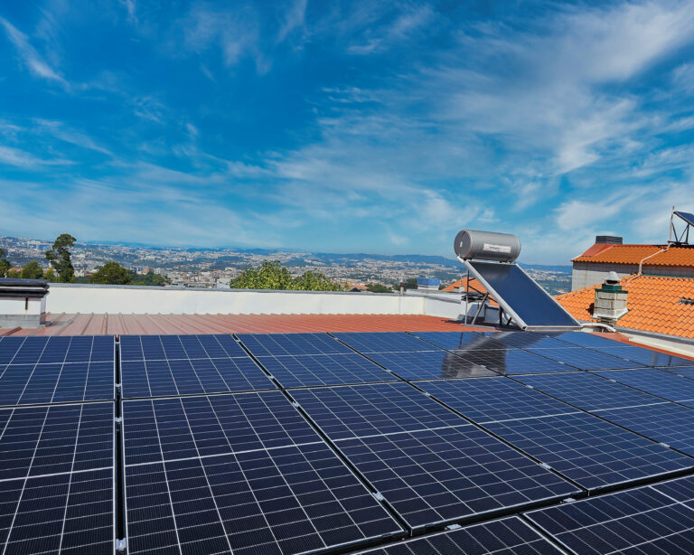 Painéis fotovoltaicos instalados numa cobertura, com vista sobre a cidade